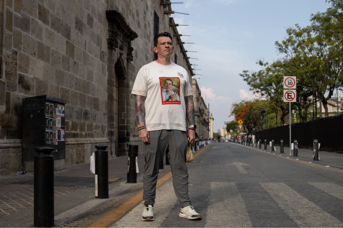Héctor Flores posa junto a estampitas con rostros de personas desaparecidas en Guadalajara