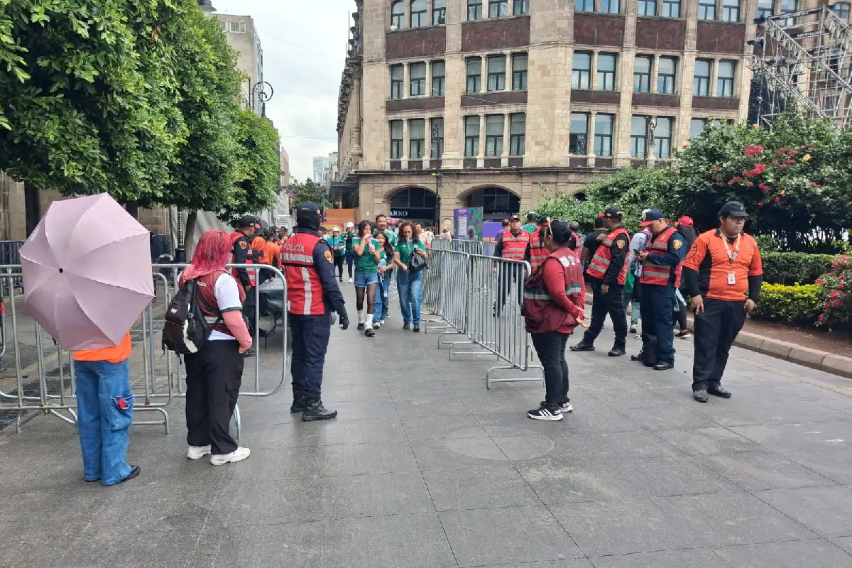 Elemenos de policía rodeando una valla por la que entran aficionados para ver el partido de mexico chequia en un fan fest