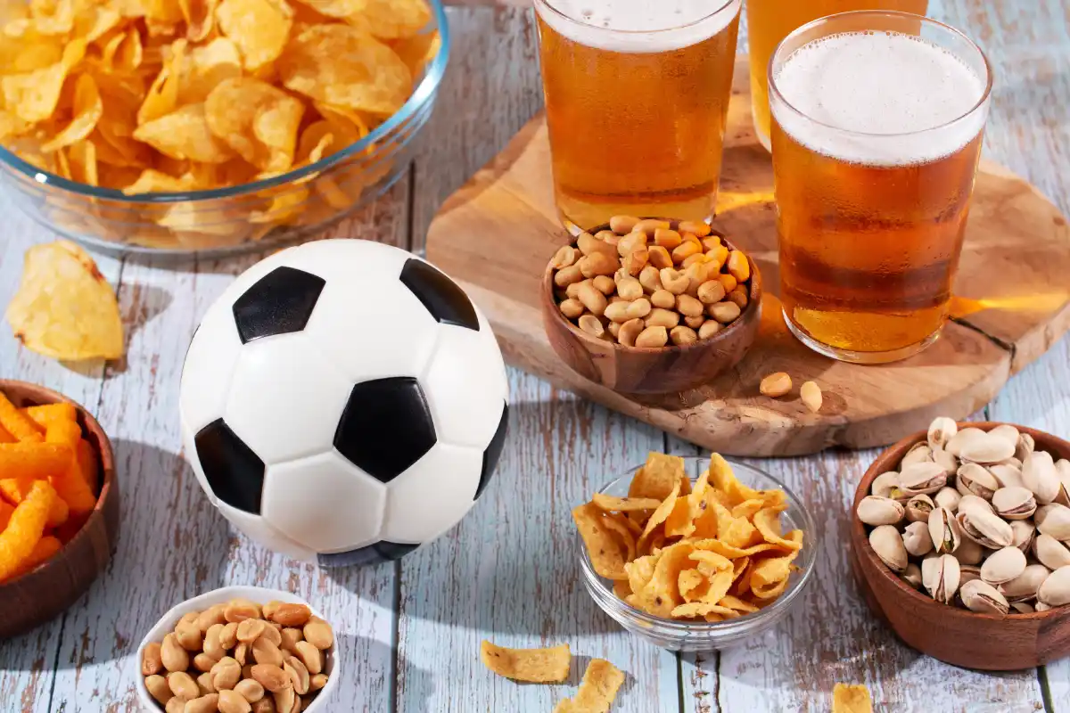 Mesa llena de snacks y un balón de futbol
