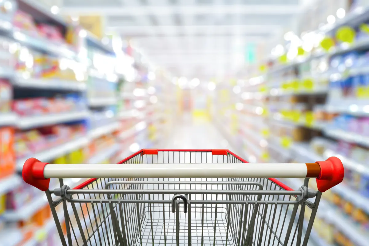 Pasarela de supermercado con carro de compras rojo vacío.