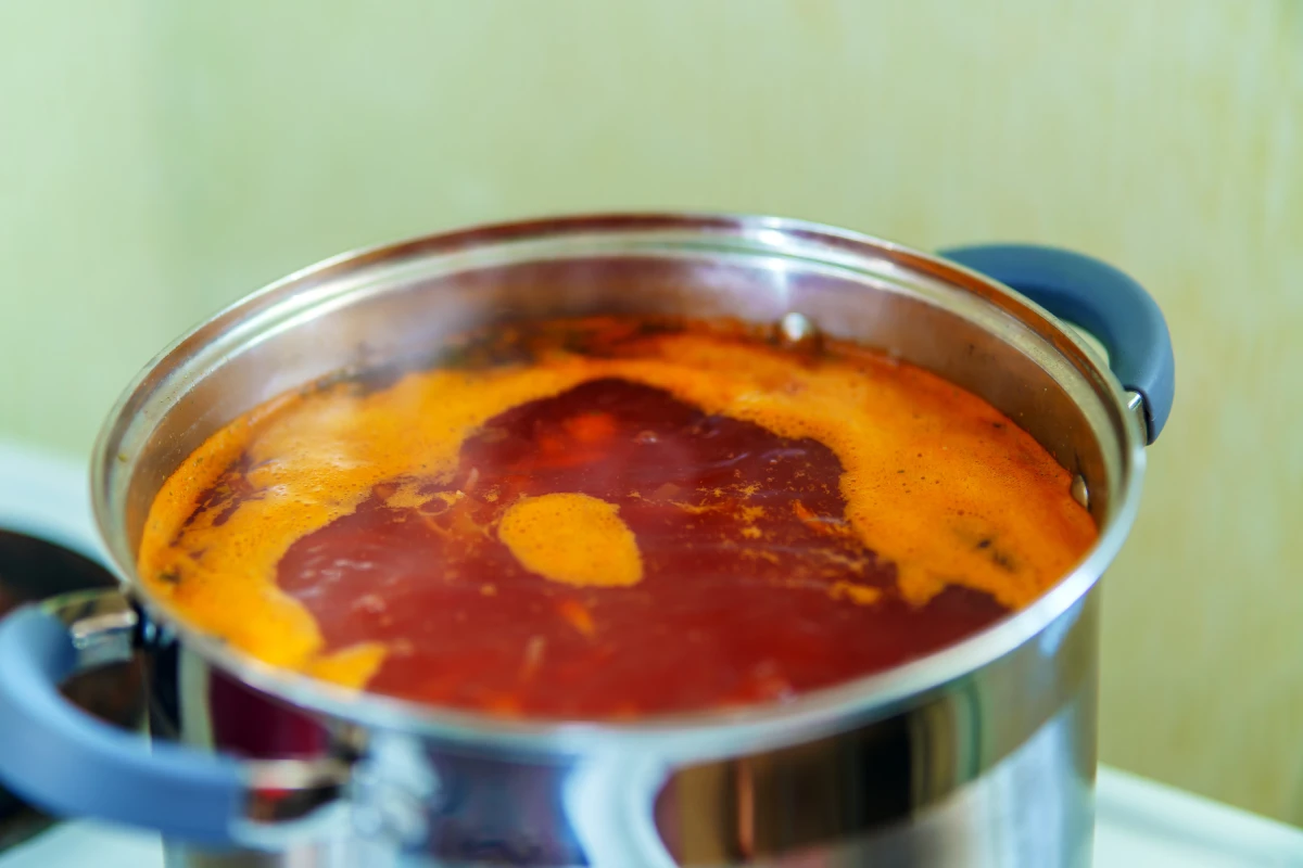 Caldo rojo hirviendo en una olla