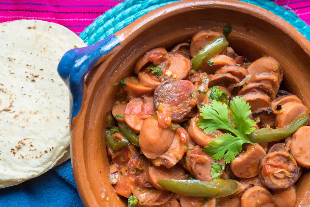 Cazuela de barro con salchichas preparadas a la mexicana