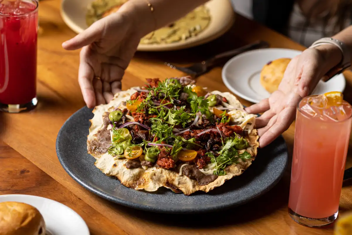 Manos dejando una tlayuda con queso oaxaca, comida tradicional mexicana de Oaxaca