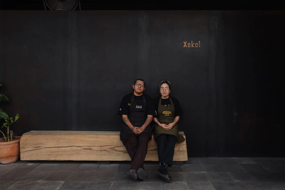 Dos personas sentadas en una banca de madera