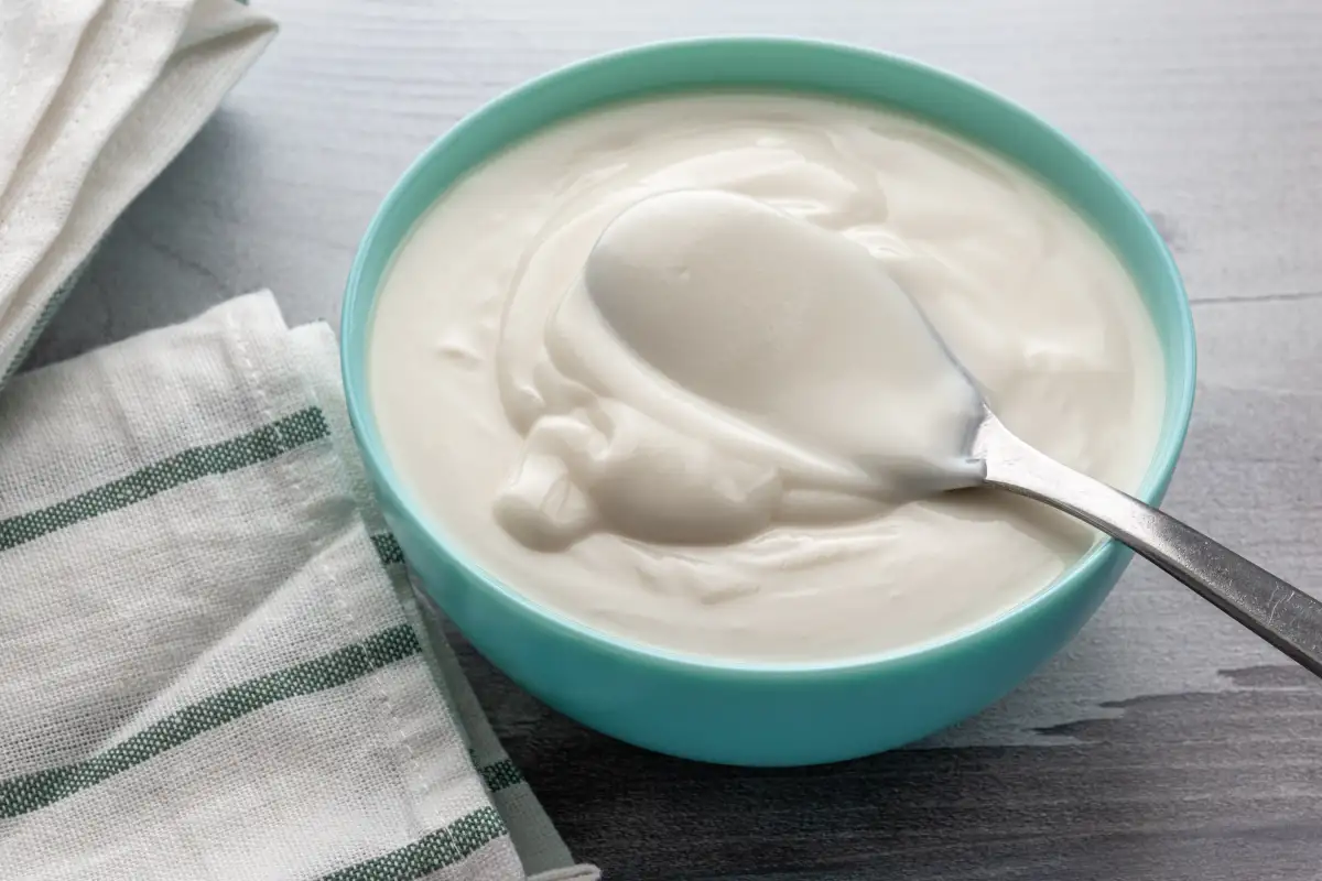 Plato azul con una cuchara agarrando yogur griego