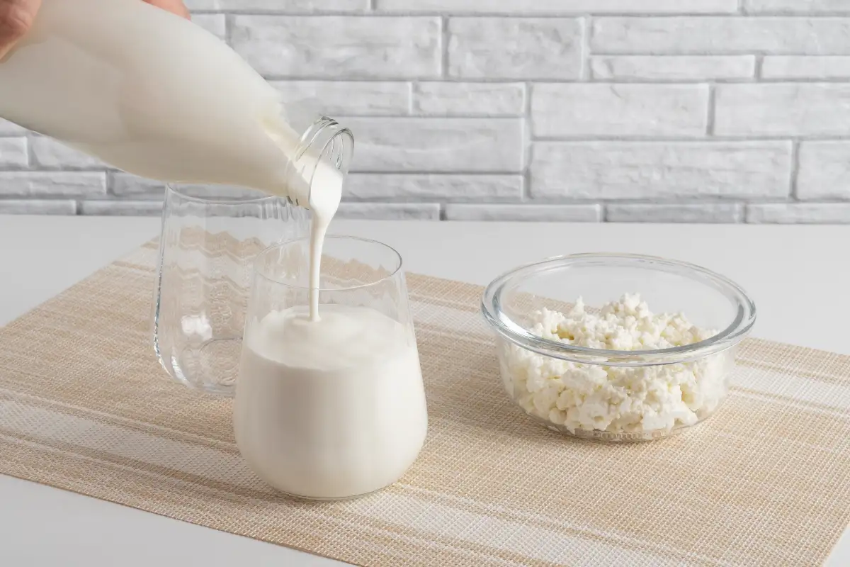 Mano sirviendo yogur griego natural sobre una jarra