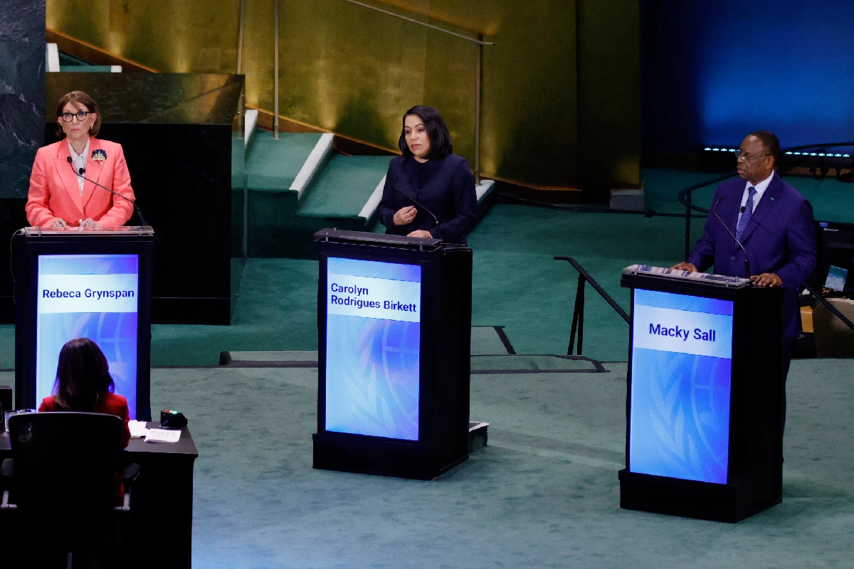 Rebeca Grynspan, Carolyn Rodrigues Birkett y Macky Sall frente a pódiums individuales con sus nombres en pantallas durante un debate en las Naciones Unidas.