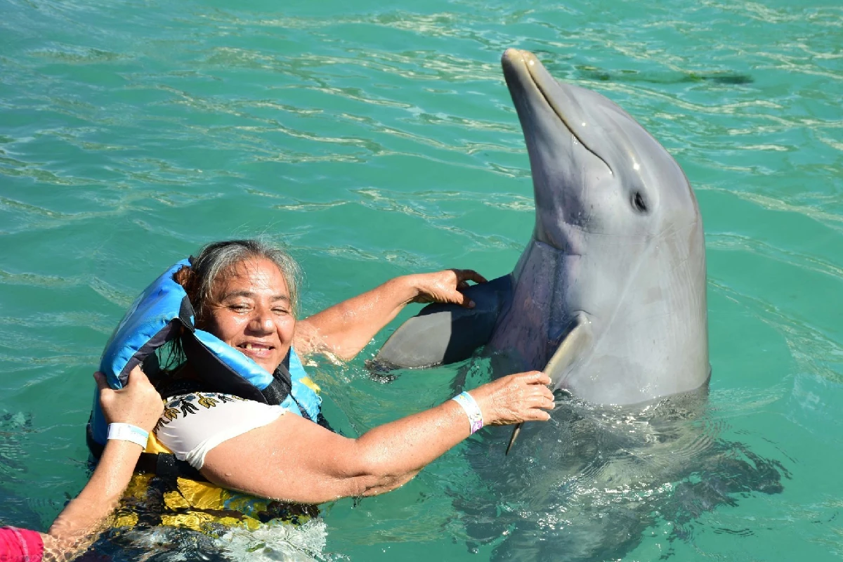 Una señora sosteniendo las aletas de un delfin 