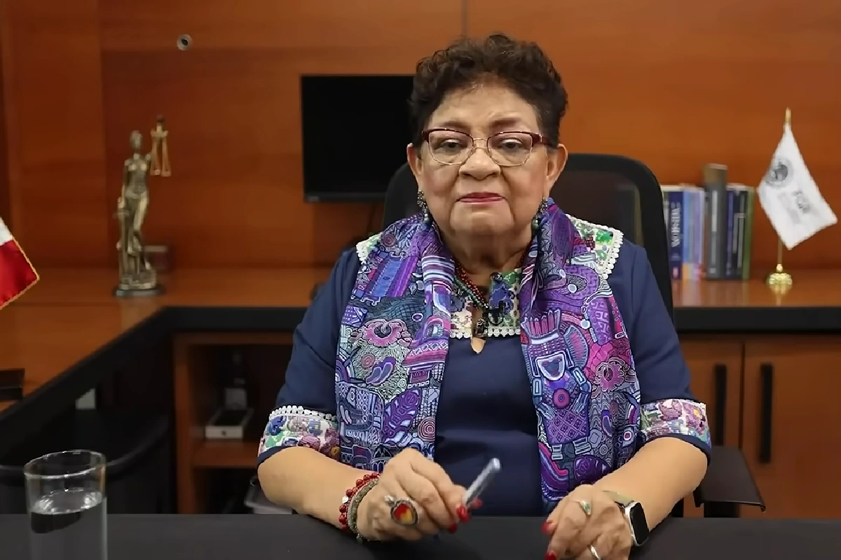 Titular de la FGR en su oficina vistindo un vestido azul con una mascada morada dando datos de la detención del exgobernador 