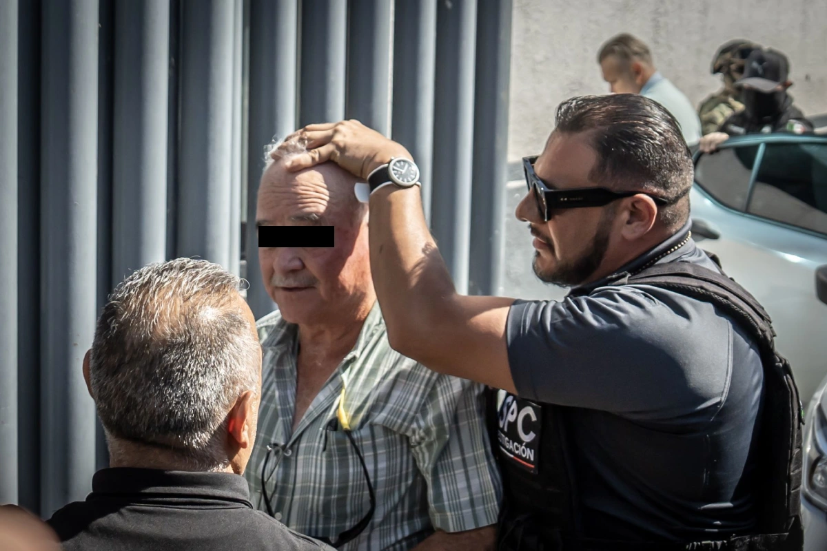 Ernesto siendo sostenido de la cabeza por elementos de seguridad para ingresar a instalaciones de la FGR