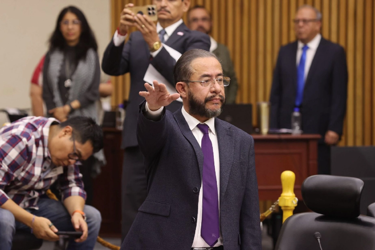 Hugo Eric Flores con el brazo estirado y la mano en señal de juramento con dos dedos abiertos 