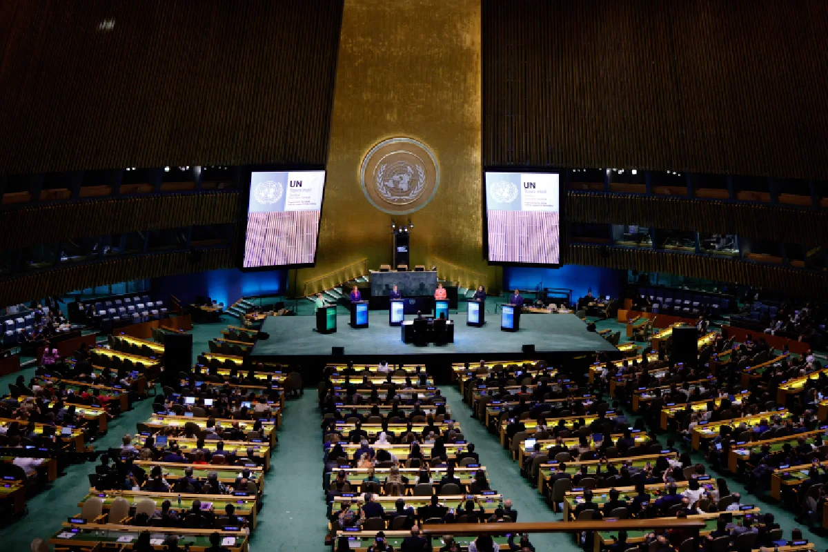 Vista panorámica del salón de la Asamblea General de la ONU con delegados sentados en sus curules y un grupo de ponentes en pódiums sobre el escenario principal.