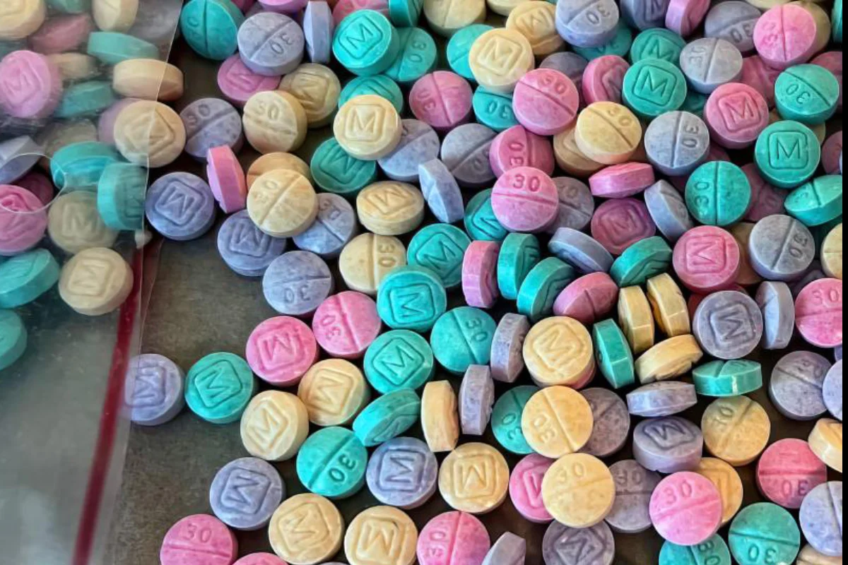 Pequeñas fastillas de fentanilo en colores morado, rosa, verde y amarillo regadas sobre una superficie 