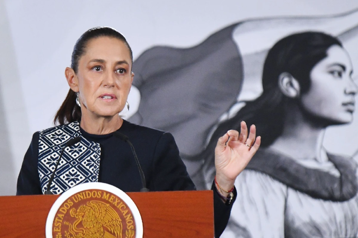 La presidenta Claudia Sheinbaum hablando en pódium presidencial gesticulando con la mano izquierda durante una conferencia matutina.