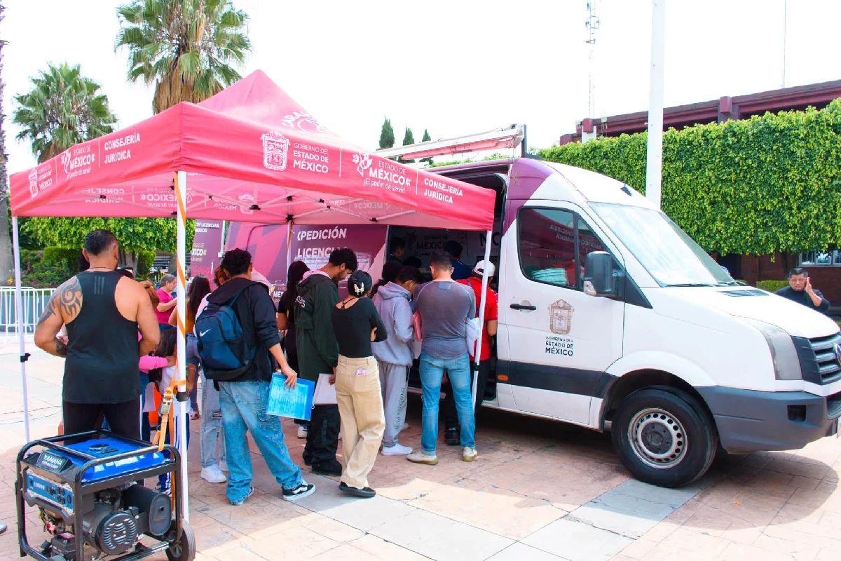 Personas haciendo fila bajo una carpa roja de la Consejería Jurídica junto a una unidad móvil del Gobierno del Estado de México para el trámite de licencias.