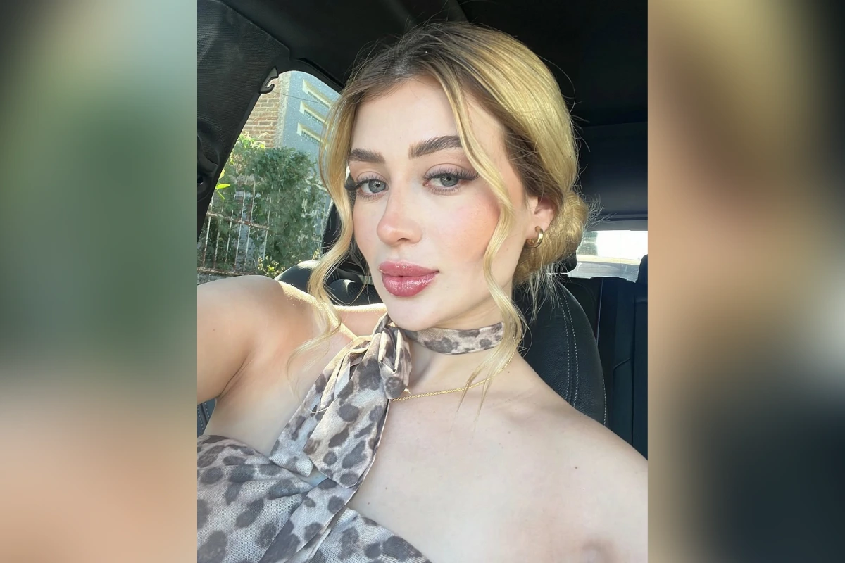 Retrato tipo selfie de Valeria Márquez con cabello rubio recogido y blusa con estampado animal print, tomada dentro de un automóvil.