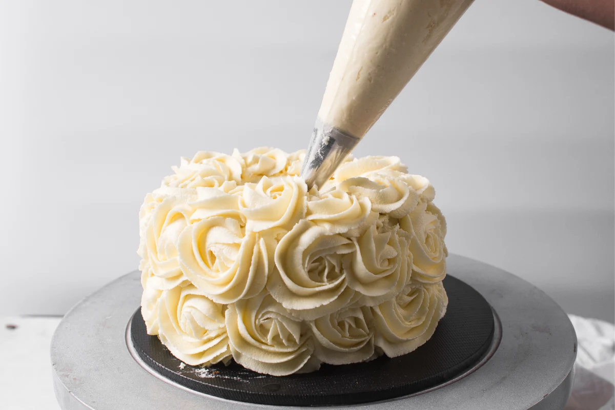 Ribeteando rosetas en un pastel usando crema de mantequilla, el pastel está cubierto de rosetas de crema de mantequilla, el pastel está cubierto de crema de mantequilla americana, proceso de decorar un pastel