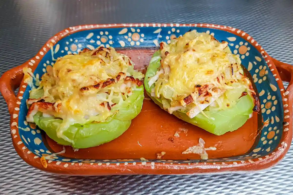Dos mitades de chayotes gratinados en un plato de barro