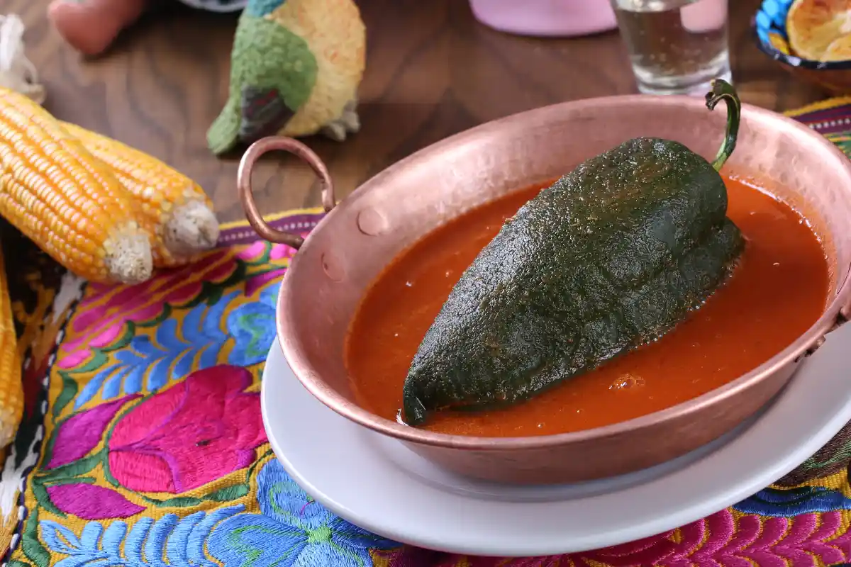 Chile poblano relleno de huitlacoche en un cazo de cobre con caldillo de jitomate
