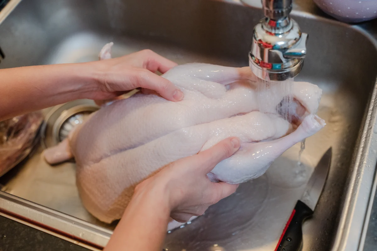 Mujer coloca un pollo entero bajo un chorro de agua