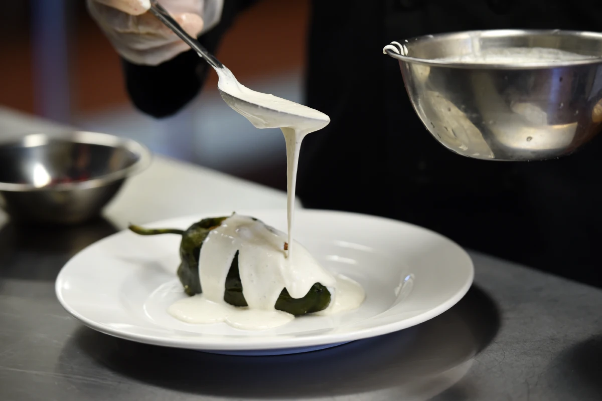 Chef vierte la nogada blanca en los chiles rellenos