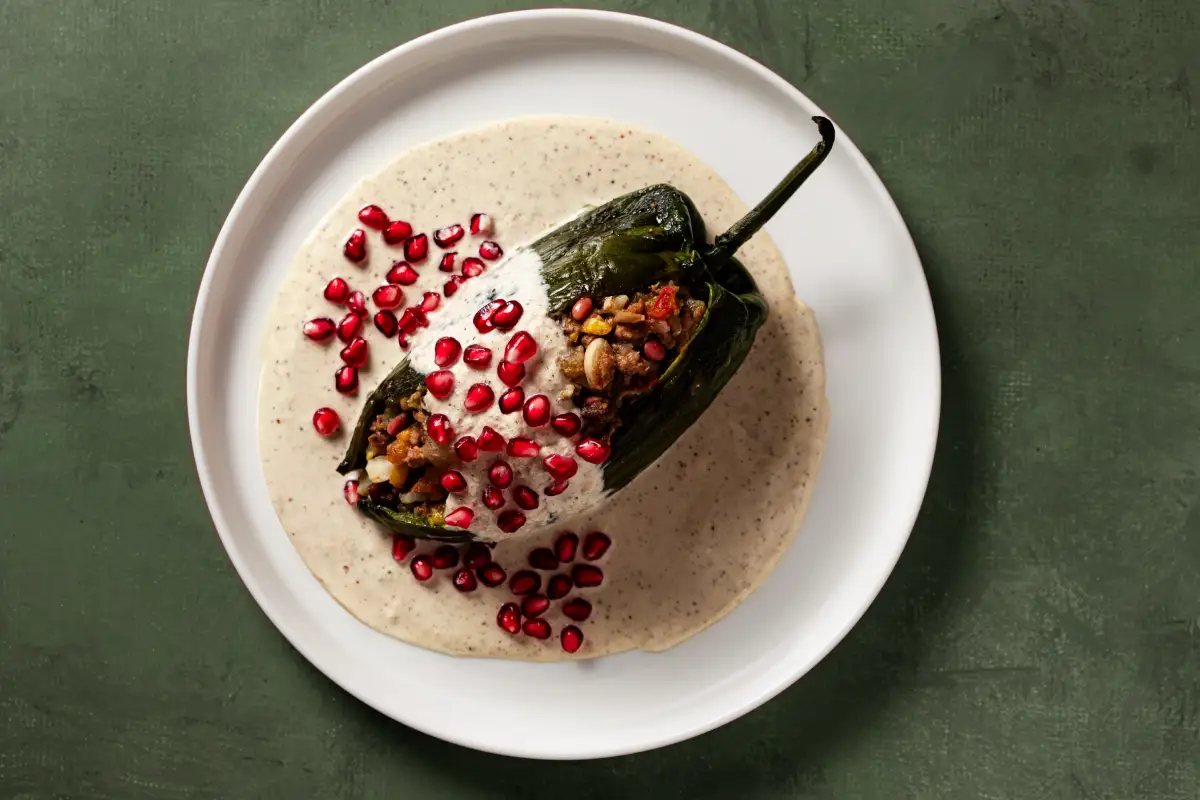 Fondo verde con plato blanco con chile en nogada