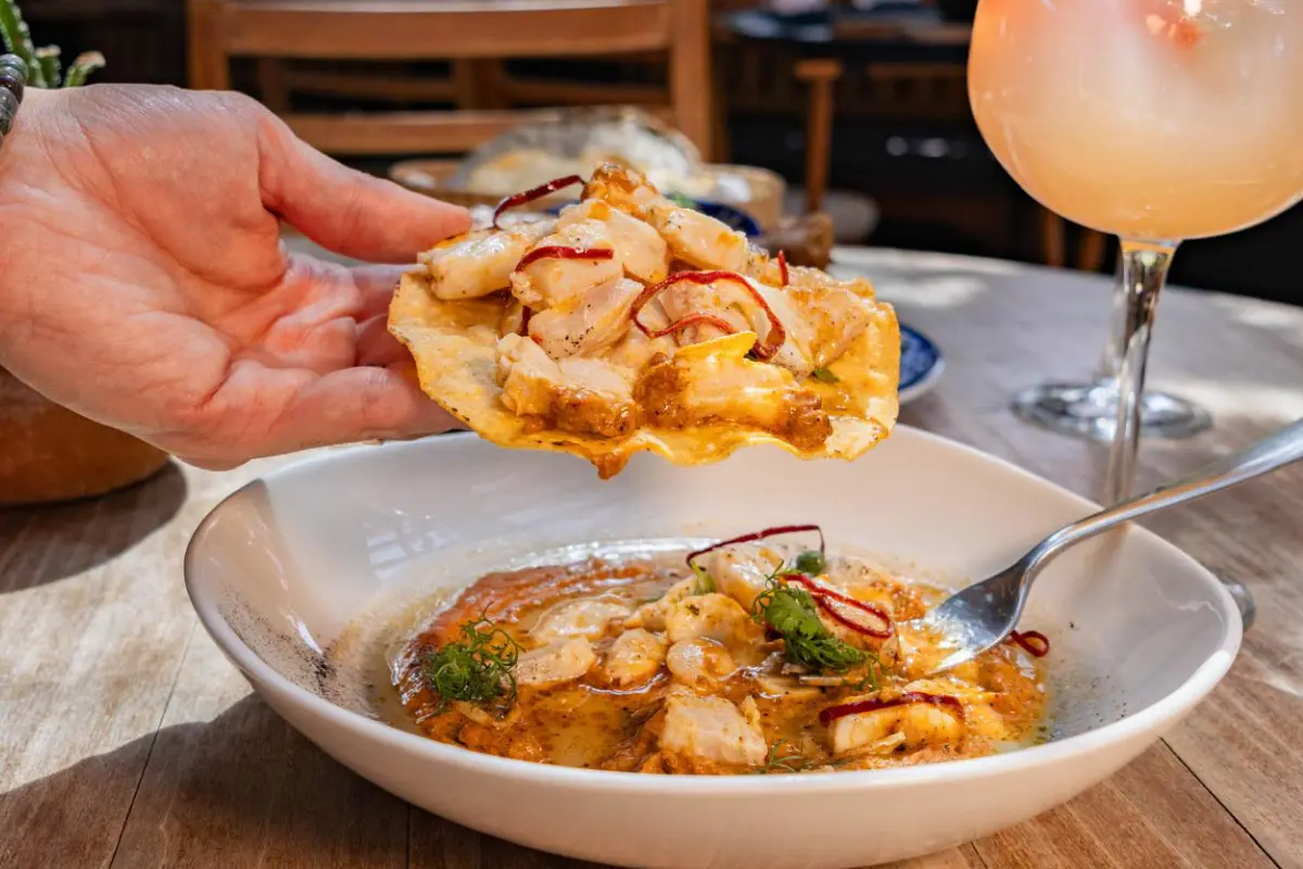 Una mano sujeta una tostada de mariscos