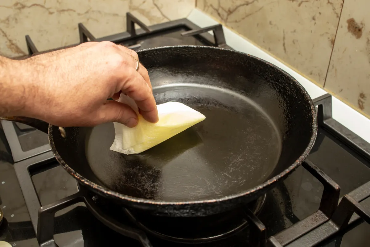 Hombre aplica aceite a un sartén de hierro fundido