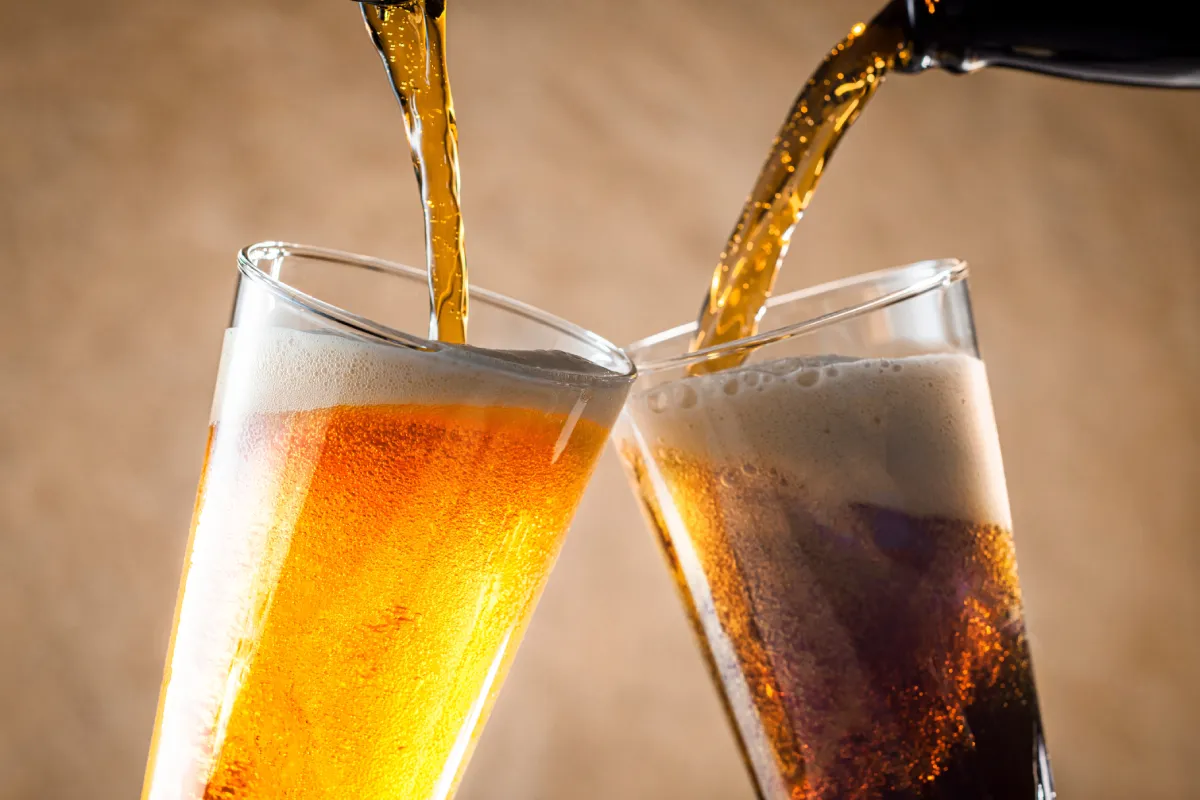 Dos tipos de cervezas siendo servidas en vasos de vidrio