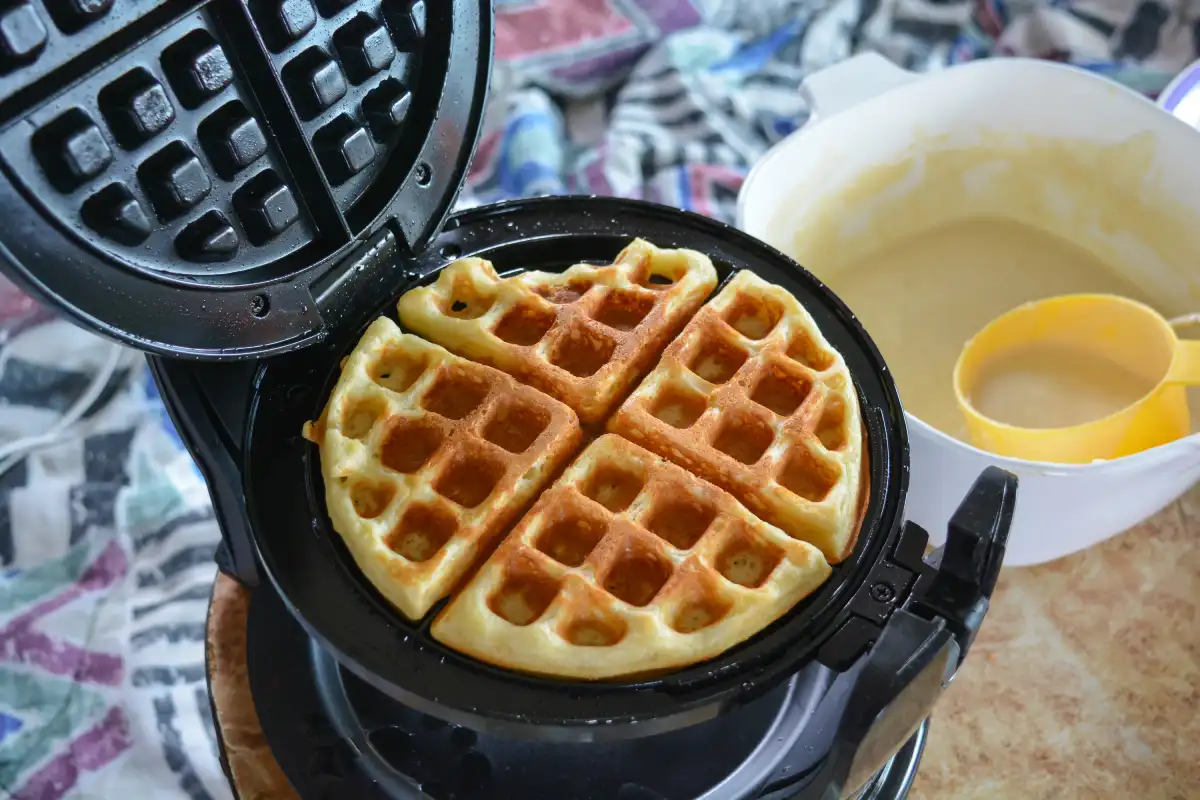 Máquina para hacer waffles junto con un bowl con mezcla