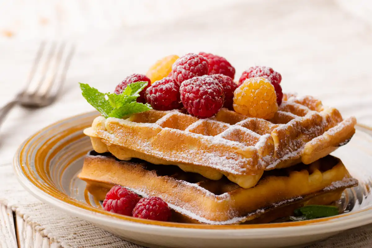 Un plato con tres waffles crujientes apilados en montaña
