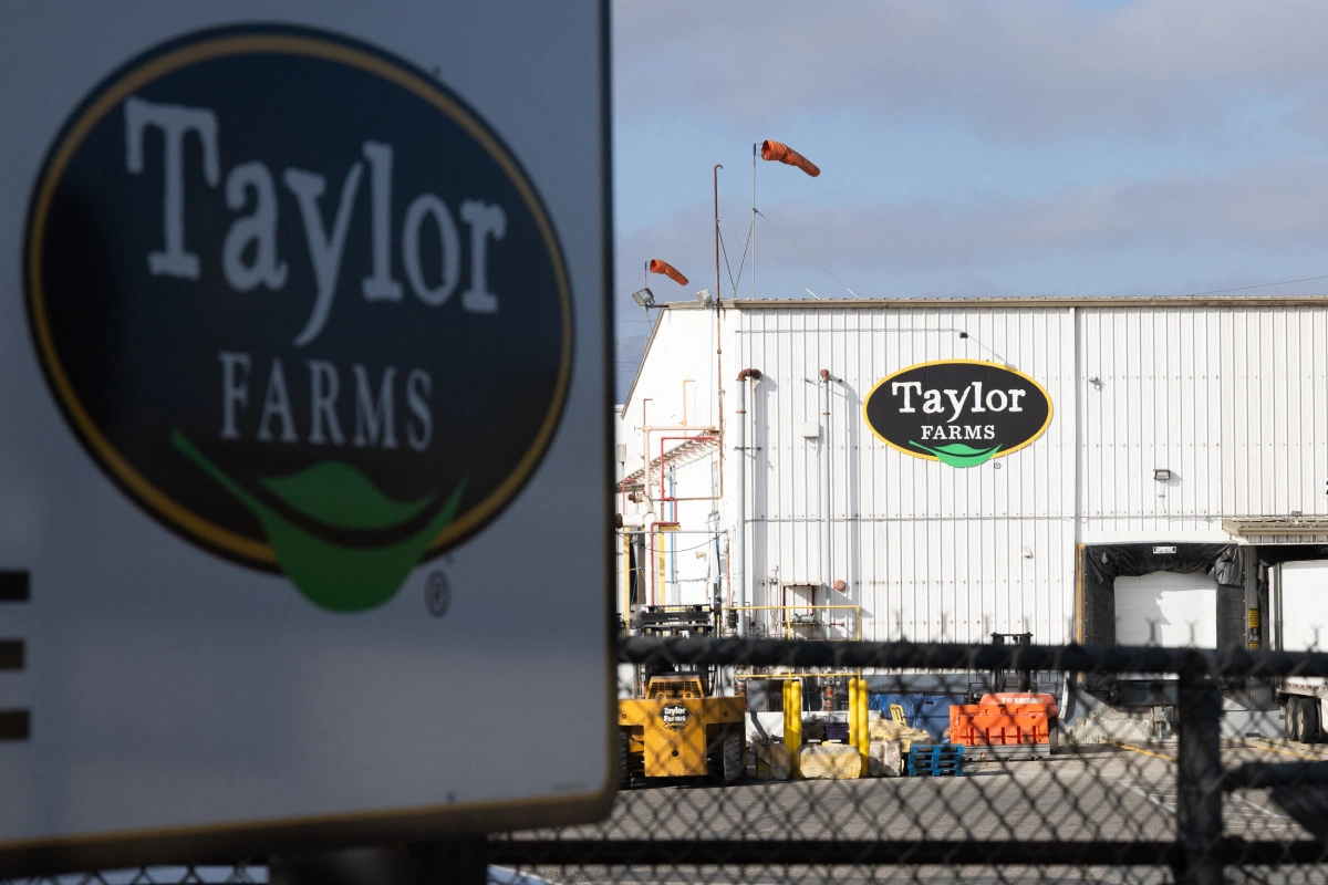 Fachada exterior de una planta de procesamiento agrícola con el letrero de "Taylor Farms" en primer plano y en el edificio industrial.
