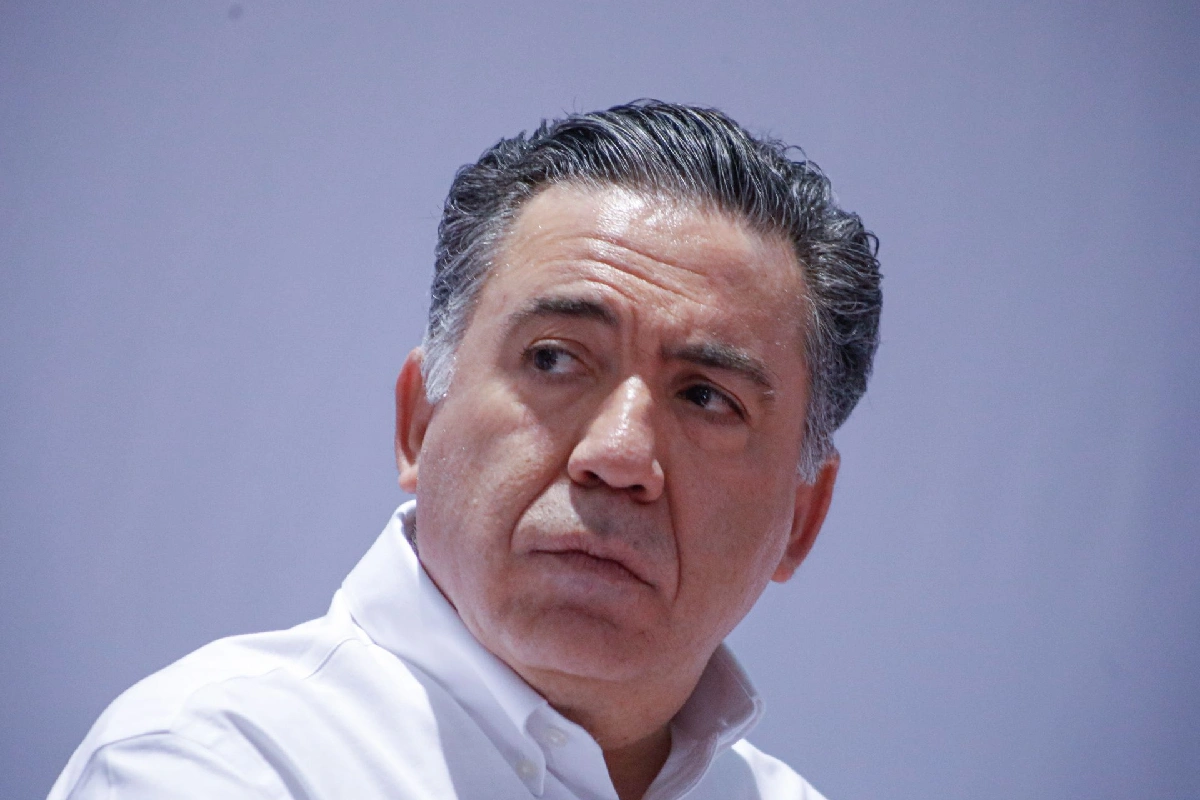Enrique Inzunza con camisa blanca mirando a la izquierda