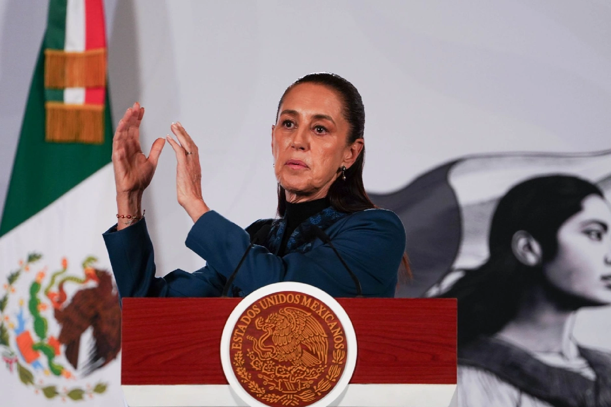 La presidenta Claudia Sheinbaum gesticulando con las manos frente al pódium presidencial con el escudo de México, durante su conferencia de prensa matutina.