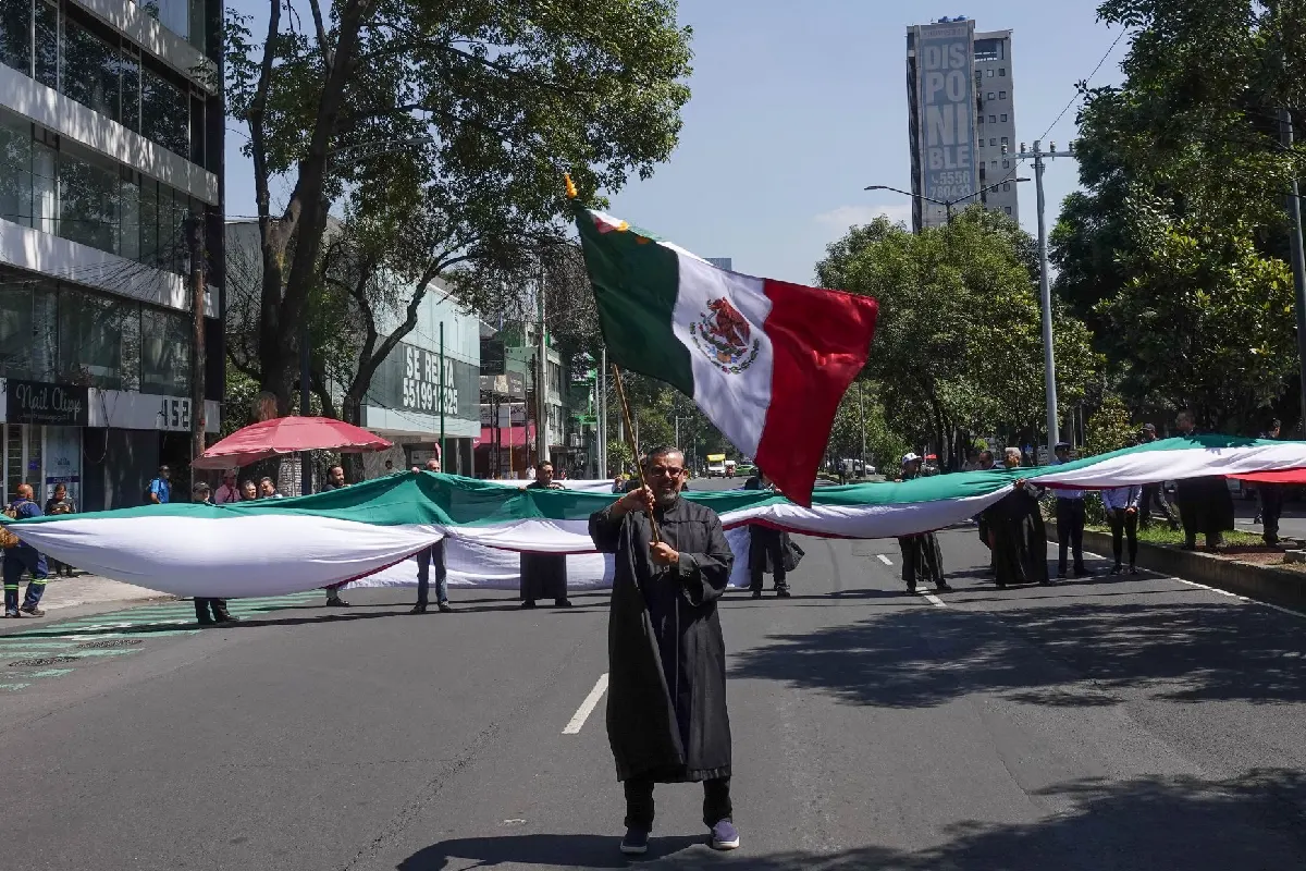 Un hombre con toga ondeando una bandera de México