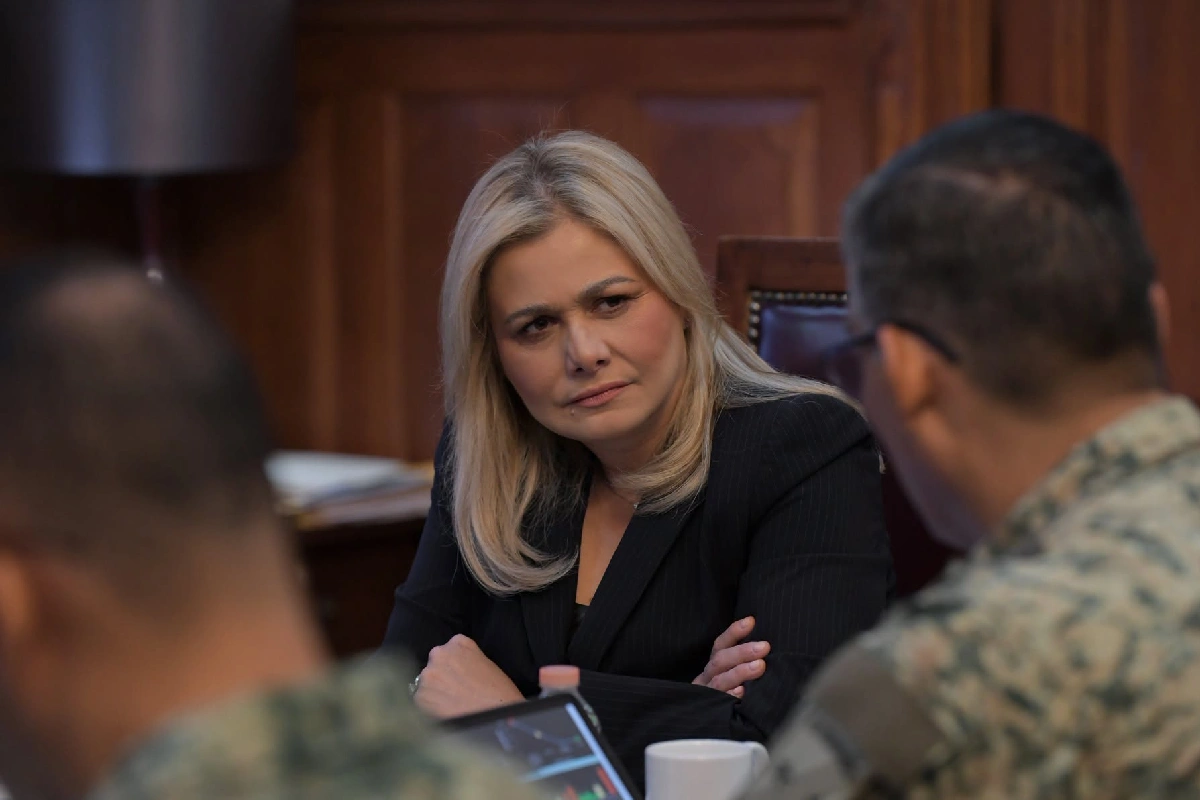Maru Campos, gobernadora de Chihuahua, sentada en una mesa de trabajo con expresión seria y brazos cruzados mientras escucha a mandos militares.