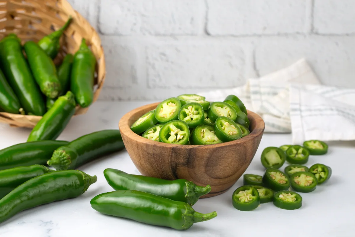 Jalapeños en rodajas en un tazón de madera aislado sobre fondo blanco