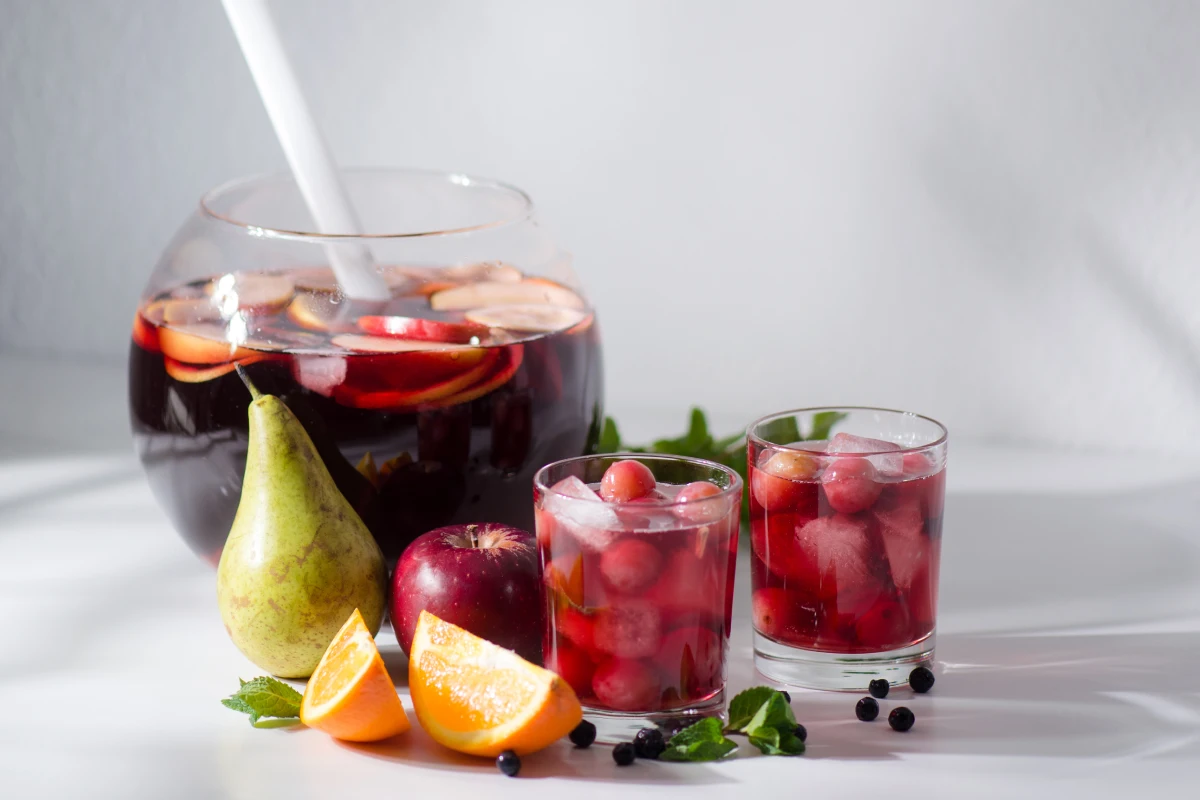 Recipiente de vidrio y dos vasos con clericot con vino tinto