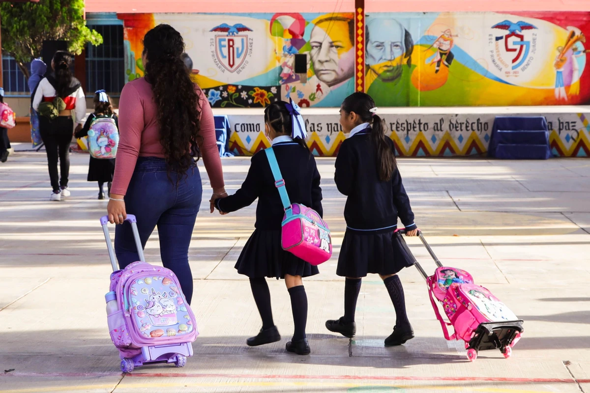 Niñas con su mamá llegando a la escuela.