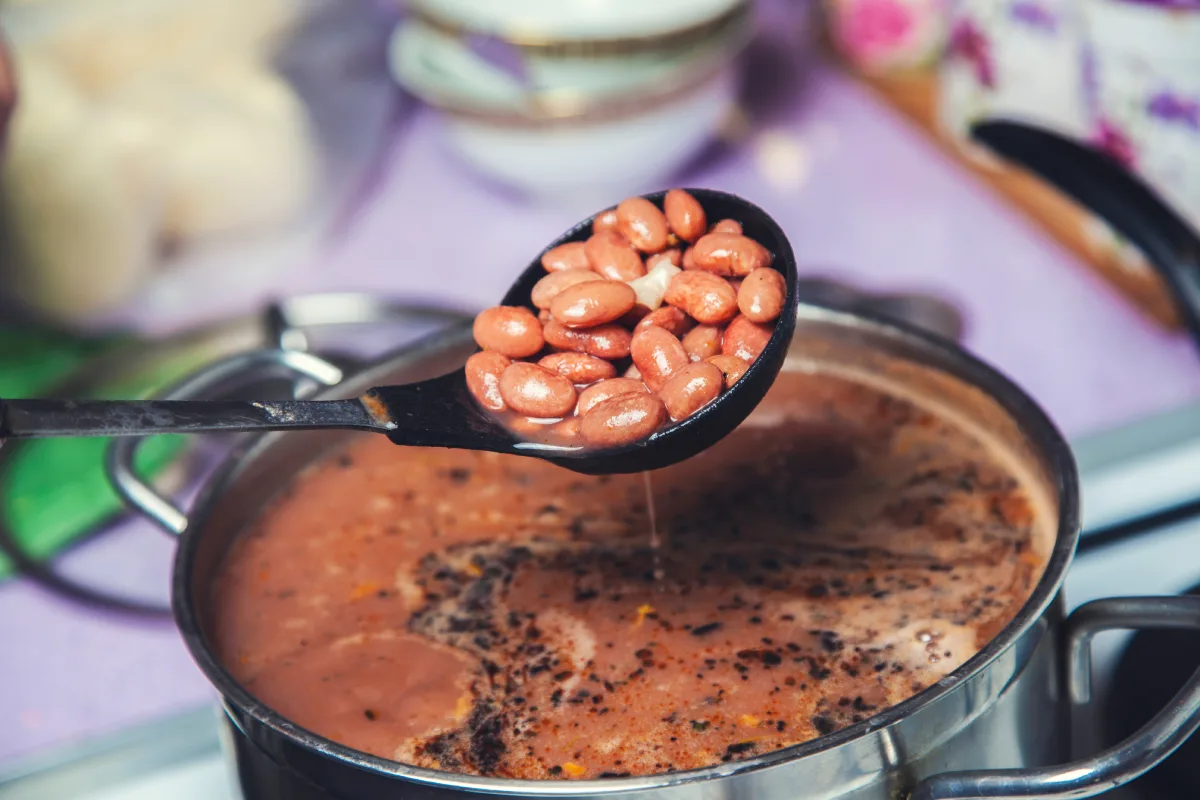Cucharón con frijoles cocidos en olla