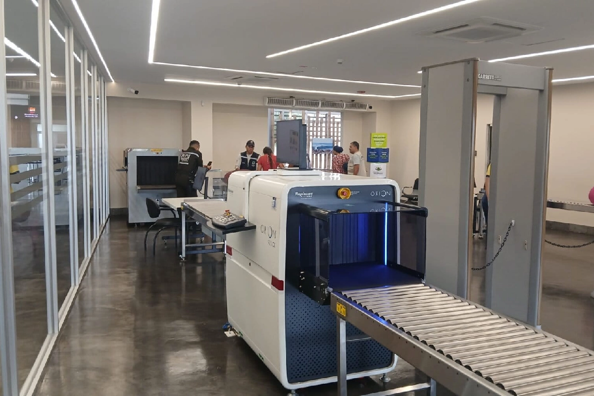 Área de control de equipaje en el Aeropuerto Seymour de Baltra, en Galápagos, por donde los tres ciudadanos tailandeses lograron cruzar con 12 iguanas marinas sin que el personal policial los detectara. Al fondo, el oficial policial encargado mira su teléfono celular mientras el personal del aeropuerto realiza los controles. (Foto: Mongabay Latam | Diego Cazar Baquero)