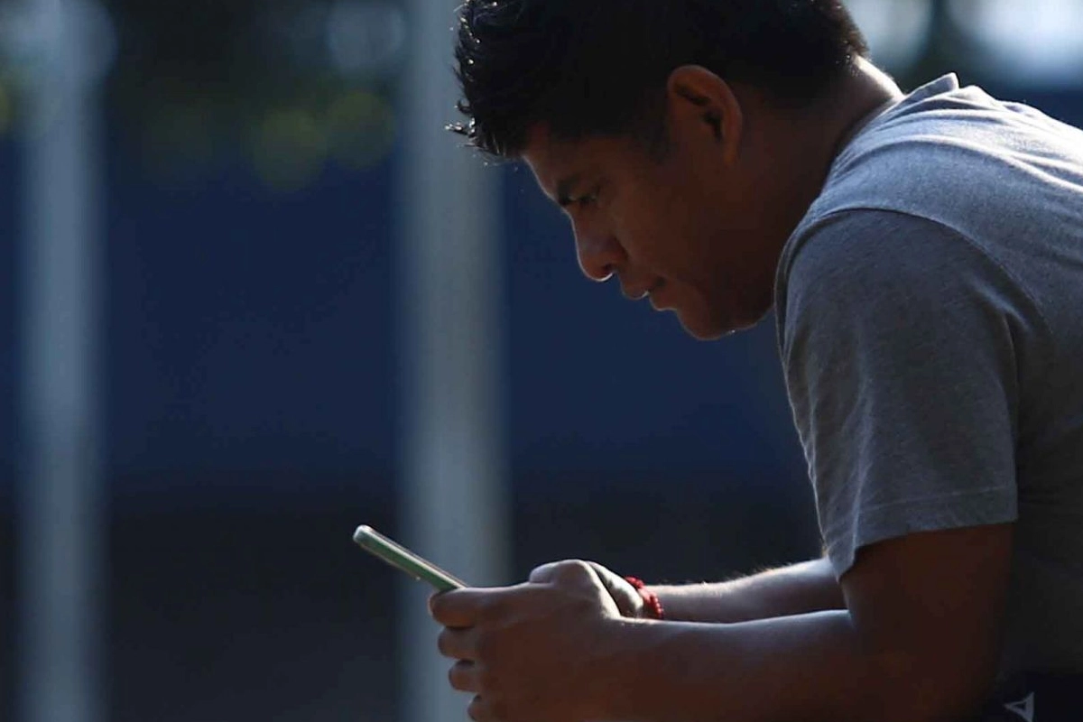 Un joven revisa su celular.