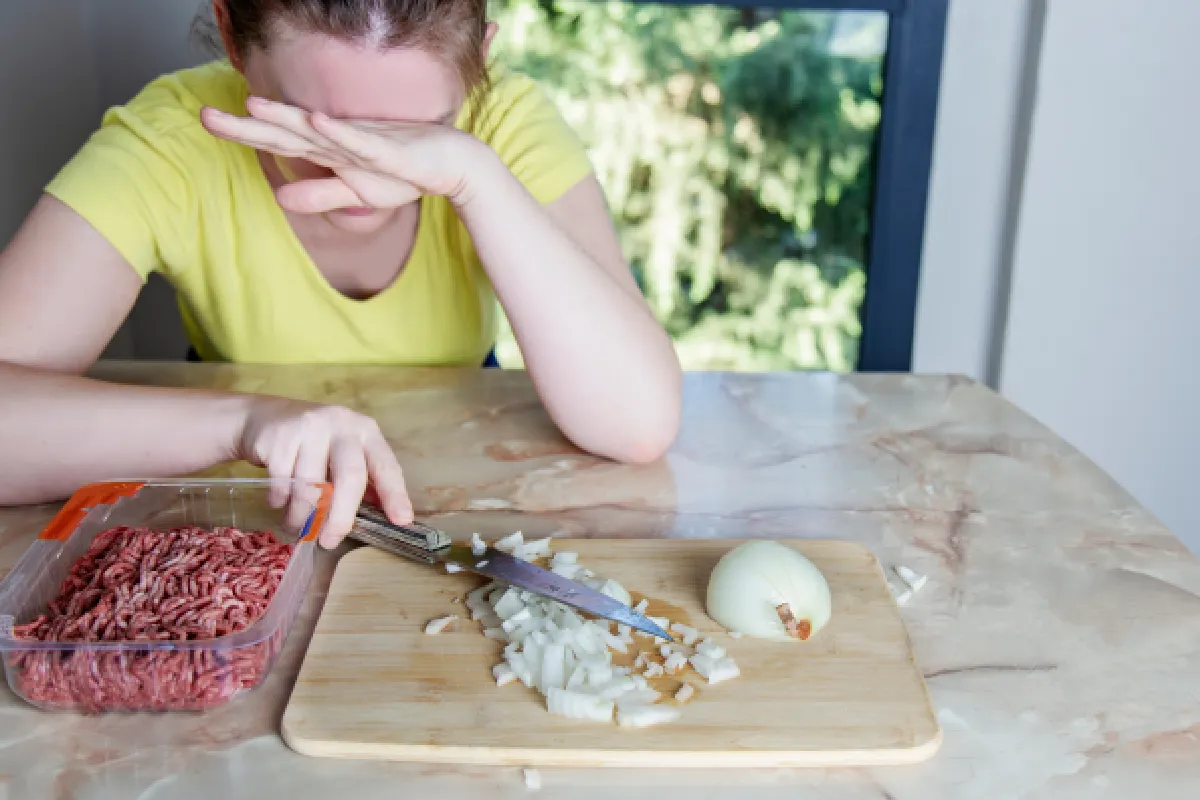 mujer picando cebolla y llorando