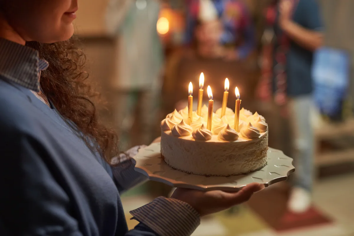 Mujer sostiene un pastel de cumpleaños con velitas encendidas