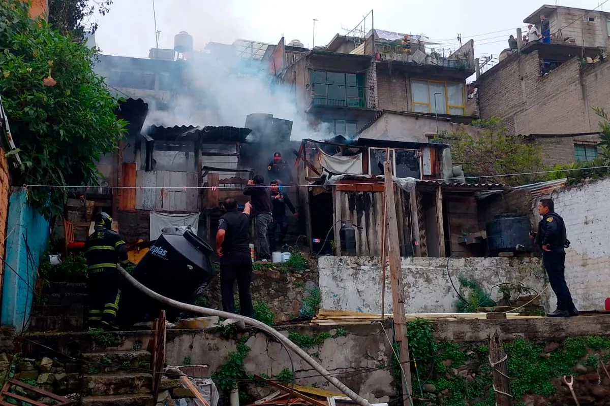 Bomberos y policías laborando entre el humo e inspeccionando las estructuras siniestradas de una vivienda tras sofocar un incendio en la alcaldía Álvaro Obregón.