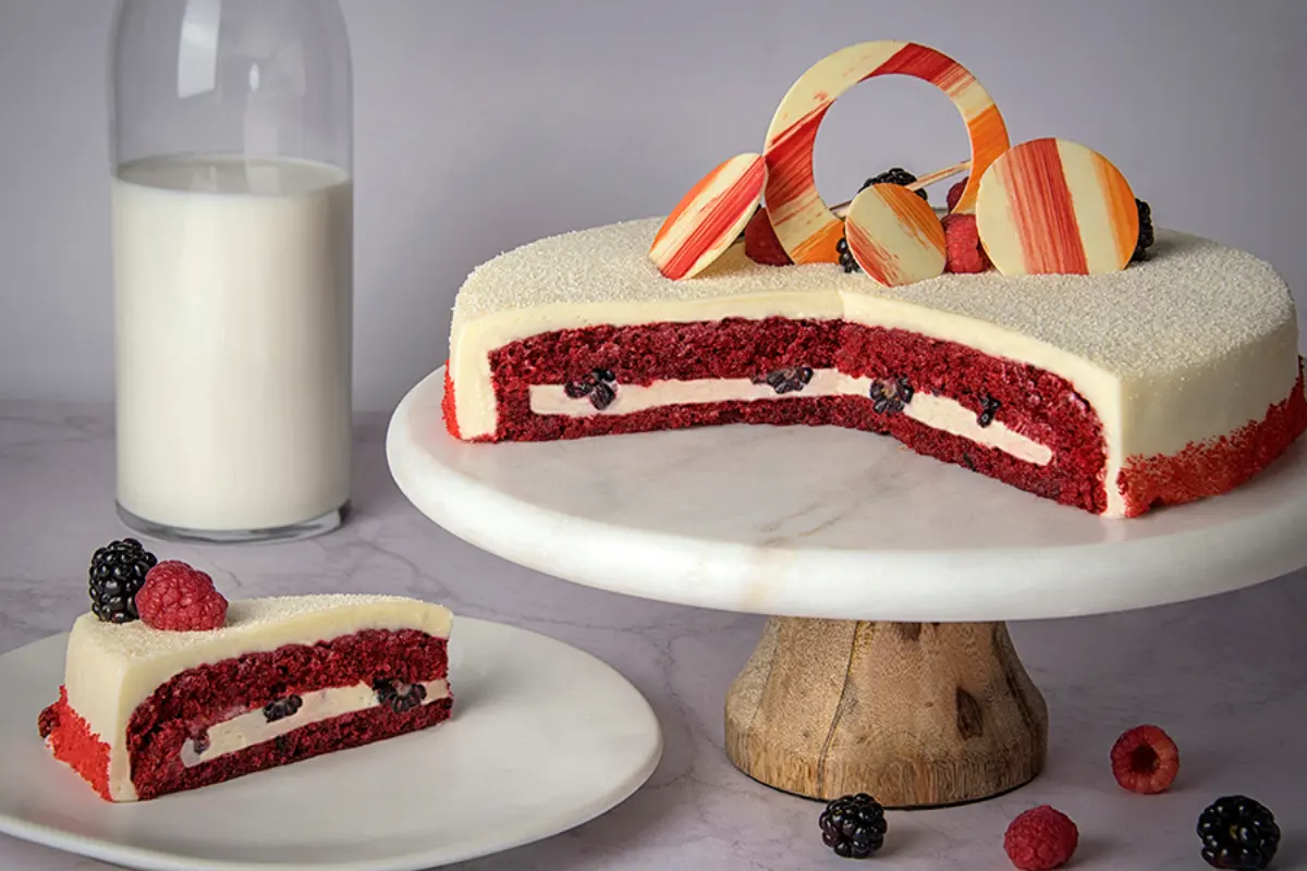 Pastel de red velvet con pan de vainilla rojo, relleno de frutos rojos con betún de queso crema y cobertura de betún blanco.
