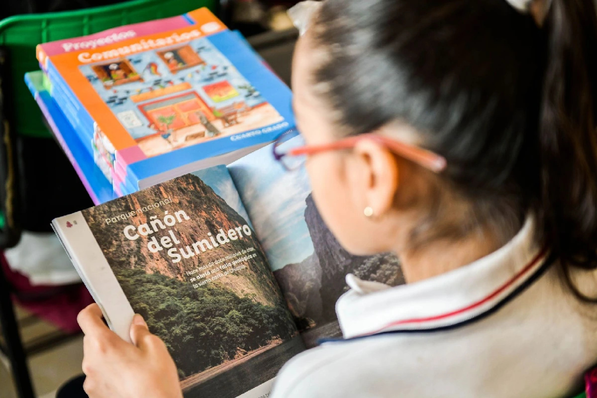 Niña viendo un libro de texto gratuiro de la sep