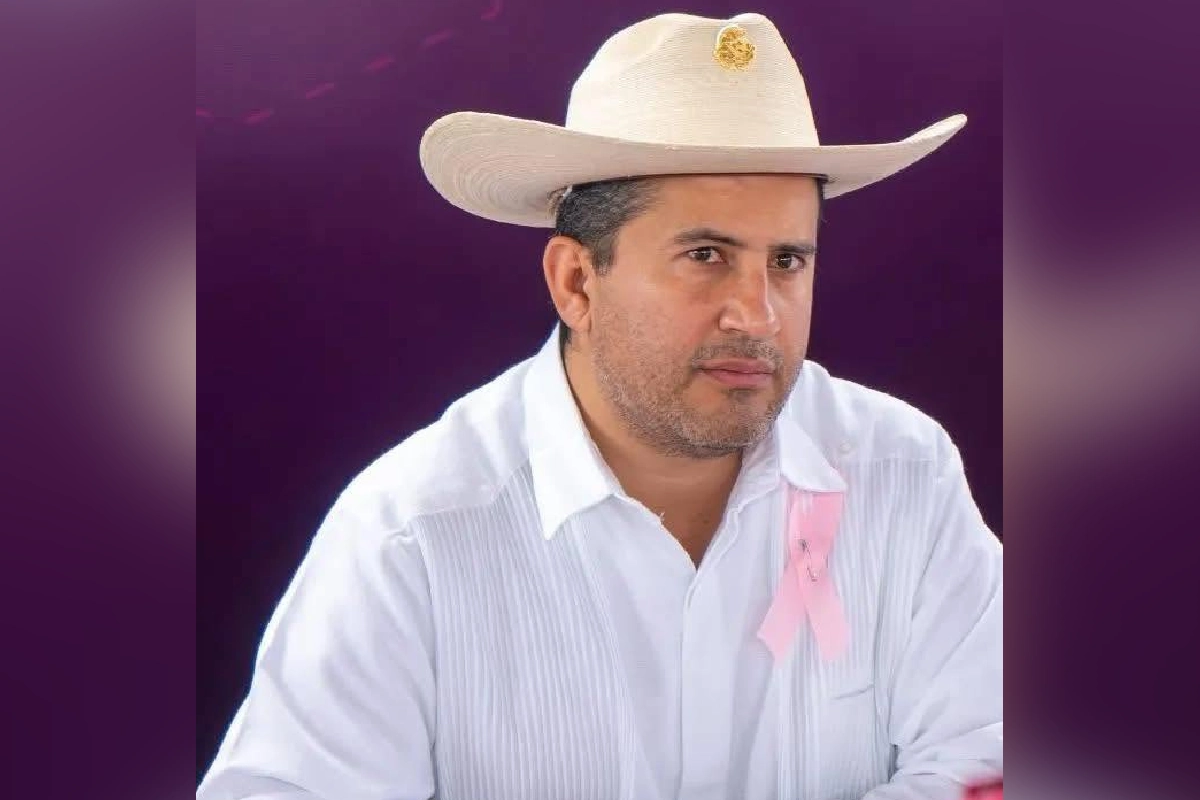Carlos Manzo usando sombrero y con un fondo morado desenfocado