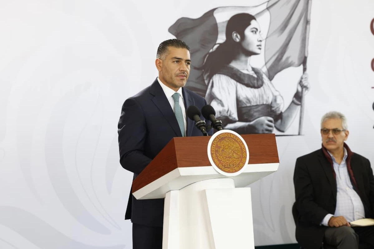 Omar García Harfuch de traje oscuro de pie en un pódium oficial con el escudo de México frente al emblema institucional, durante un informe de seguridad.