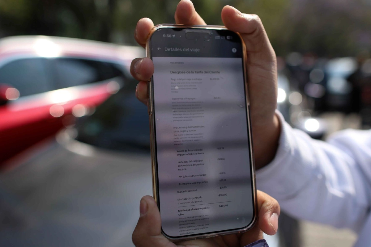 Un conductor mostrando en su celular el desglose de la tarifa que se cobra a usuarios